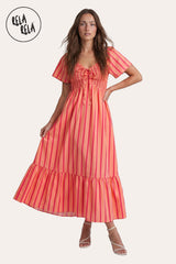 Front view of a model wearing the Orange Stripe Smocked Maxi Dress, highlighting the tangerine vertical stripes and the adjustable lace-up neckline.