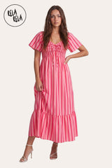 Front view of a model wearing the Pink Stripe Smocked Maxi Dress, highlighting the lace-up tie detail, flutter sleeves, and the vibrant vertical candy stripes.