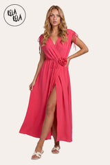 Front view of a model wearing the Coral Flower Corsage Wrap Maxi Dress, showcasing the vibrant sunset-hued drape and the 3D floral waist detail.