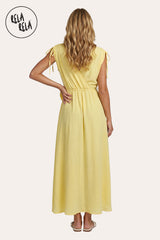 Back profile of the yellow maxi dress, showcasing the fluid movement of the skirt and the delicate ruched shoulder detailing.
