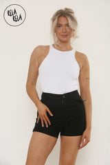 Model wearing black high waisted denim shorts with turn-up hem