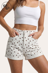 Front view of a model wearing Rela Rela's White Polka Dot sculpting high-waisted denim shorts. Highlights the flattering waistband, playful dot print, and permanent turn-up cuff.