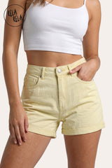 Front view of a model wearing Rela Rela's Lemon sculpting high-waisted denim shorts. Highlights the soft yellow shade, flattering waistband, and turn-up cuff.