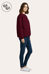 Side view showing the relaxed oversized fit and long sleeve design of the burgundy ruched hem jumper.