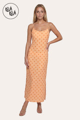 Front view of a model wearing the Orange Retro Polka Dot Slit Maxi Slip Dress, highlighting the vibrant citrus-orange hue and the minimalist scoop neckline.