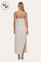 profile of the model in the Polka Dot Slip Dress, showcasing the fluid movement of the maxi skirt and the high-cut slit for effortless walking.