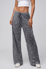 Front model view of grey sparkling sequin trousers with an elasticated drawstring waistband and wide legs.