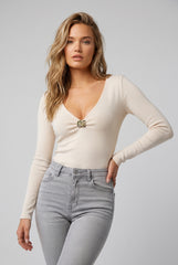 Front model view of the RELA RELA cream ribbed V-neck long sleeve top with gold-tone buckle detail.