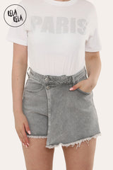 Front view of women's grey asymmetric denim skorts with mid-rise waist and frayed hem