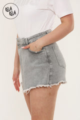 Side angle of asymmetric grey denim skorts with front buttons and frayed hem