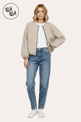 Model wearing oversized beige zip-up bomber jacket pair with jeans