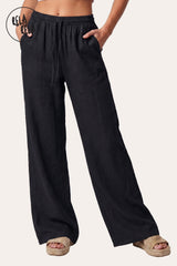 Front view of a model in Rela Rela’s Black high-waisted linen trousers, showcasing the slimming wide-leg silhouette and the sleek drawstring waist.