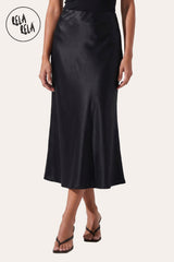 Front view of a model wearing Rela Rela’s Black satin maxi skirt with a slim straight cut. Highlights the elegant high-waisted fit and the lustrous, silky finish of the premium satin fabric.