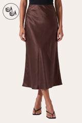 Front view of a model wearing Rela Rela’s Chocolate satin maxi skirt with a slim straight cut. Highlights the elegant high-waisted fit and the lustrous, silky finish of the premium satin fabric.