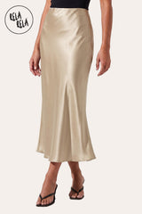 Front view of a model wearing Rela Rela’s Champagne satin maxi skirt with a slim straight cut. Highlights the elegant high-waisted fit and the lustrous, silky finish of the premium satin fabric.