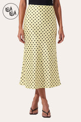 Front view of a model wearing Rela Rela Yellow satin polka dot flowy maxi skirt. Highlights the high-waisted fit and the vibrant, luminous finish of the fabric.