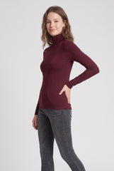 Angled model view of the burgundy slim fit roll neck long sleeve top.