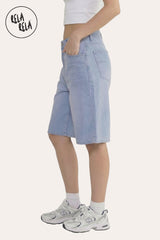 Side view showing the relaxed baggy fit and longline silhouette of the blue denim shorts.