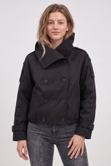 Front model view of a black cropped double-breasted trench jacket with a large collar, shoulder tabs, button front and buckled cuffs.