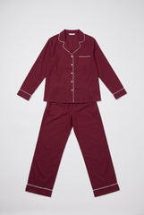 Flat product view of a burgundy long sleeve pyjama set showing the notched collar, white piping, button-through shirt and matching long trousers.