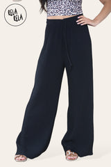 Close-up of black plissé fabric – textured detail of pleated wide leg trousers.