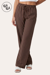 Front view of a model wearing RELA RELA Chocolate pinstripe relaxed-fit trousers, with an elasticated high-rise waistband, side pockets and a full-length wide-leg drape on a clean white backdrop.