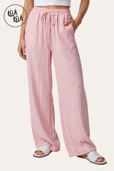 Front view of a model wearing RELA RELA Pink pinstripe relaxed-fit trousers with an elastic waistband, side pockets and wide-leg drape.