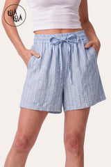 Front view of a model wearing Rela Rela's Baby Blue vertical striped flowy loungewear shorts. Highlights the stretchy elastic waistband, faux linen fabric, and the relaxed flowy silhouette.
