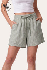 Front view of a model wearing Rela Rela's Sage vertical striped flowy loungewear shorts. Highlights the stretchy elastic waistband, faux linen fabric, and the relaxed flowy silhouette.