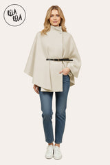 Model wearing beige belted high neck poncho cape jacket paired with jeans.