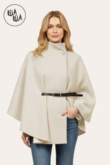 Front view of beige belted poncho cape jacket with high neck and button closure.