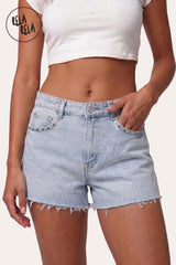 Front view of model wearing RELA RELA Baby Pink Star Diamante Light Wash Denim Shorts, featuring button closure, front pockets with silver-tone hardware, and raw distressed hem.