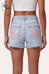 Back view of model wearing RELA RELA Baby Pink Star Diamante Light Wash Denim Shorts, featuring twin back pockets adorned with statement baby-pink star diamante embellishments and raw distressed hem.