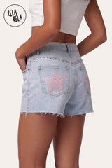 3/4 back-side angle of model wearing RELA RELA Baby Pink Star Diamante Light Wash Denim Shorts, showcasing the side and back pocket star detailing with the flattering vintage straight-leg silhouette.