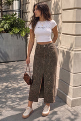 Model wearing a high-waisted leopard-print maxi denim skirt with a front slit, styled with a white T-shirt and cream trainers.