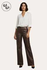 Model wearing chocolate faux leather dad fit wide leg trousers with a blouse top.