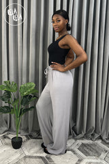 Side view of full-length grey plissé wide leg trousers – flattering pleated wide leg trousers elongating the legs.