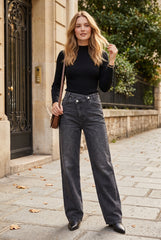 Woman wearing dark grey cross waist high-waisted straight leg jeans with black turtleneck top on Parisian street