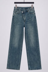 Flat lay of RELA RELA Denim Blue asymmetric waist wide-leg jeans, showing the crossed waistband, button detail and washed blue denim texture.