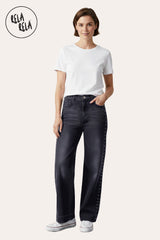 Model wearing stretchy studded rivet wide leg jeans in charcoal, paired with fitted top and sneakers.