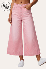 RELA RELA Pink baggy fit longline denim jorts worn on body, three-quarter front view cropped from waist to mid-shin showing soft Pink wide-leg denim with silver metal button at the waistband, one hand tucked into the front pocket, paired with white sneakers