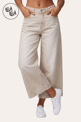 RELA RELA Beige baggy fit longline denim jorts worn on body, cropped view from waist to mid-shin showing the warm Beige wide-leg denim, both hands tucked into the front pockets, paired with cream-coloured sneakers