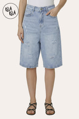 Front view of a model wearing Rela Rela Light Blue baggy fit longline denim shorts. Highlights the distressed ripped details and the oversized 90s jorts silhouette.