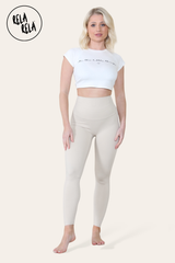 Model stretching in beige high waisted workout leggings, showing flexibility